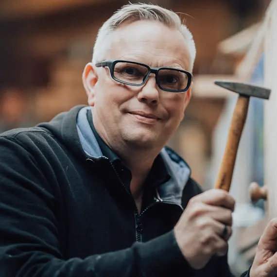 Tim Findeisen Arbeitsschutzbrille hämmert einen Nagel in die Wand