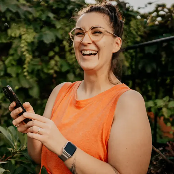 Lachende Frau mit einer Digitalbrille am Smartphone