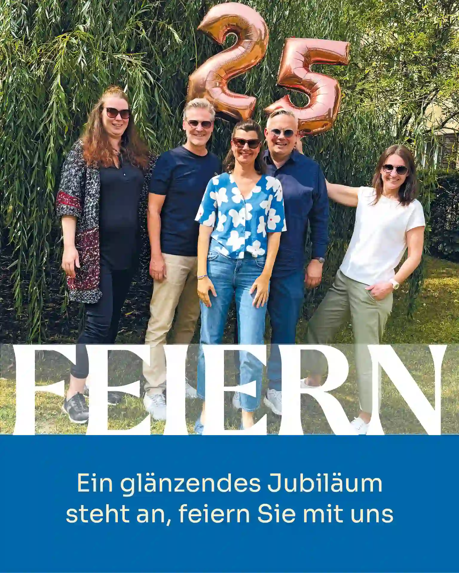 das Team von Augenoptik Findeisen stehend vor einem Baum mit kupferfarbenen Ballons mit der Zahl 25